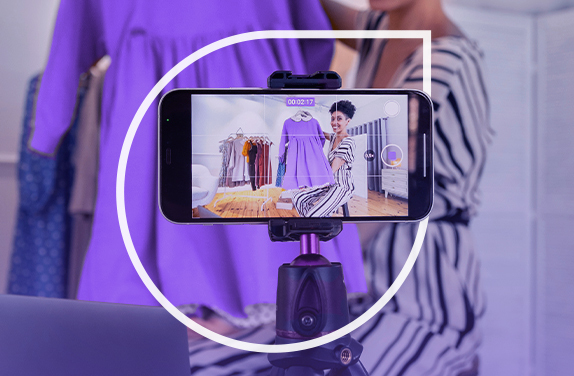 Capa de Blog "Anúncios em vídeo no Meta Ads" com um smartphone mostrando imagem de uma moça segurando um vestido roxo.