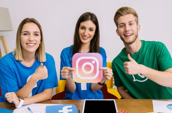 três pessoas com logotipos de redesocial para representar a tendência de marketing UGC
